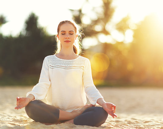 A woman meditating with a lens flare from the sun.